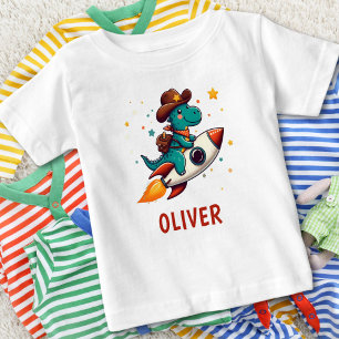 かわいい恐竜カウボーイが宇宙ロケットに乗っている ベビーTシャツ