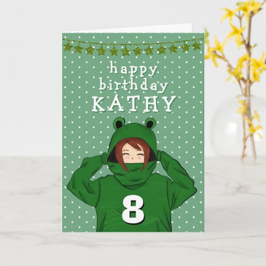 かわいい緑のカエルフードを着た女の子の誕生日絵 カード (黄色い花)
