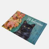 かわいい黒猫の子ネコの赤は青いドアの歓迎を残します ドアマット (アングル)