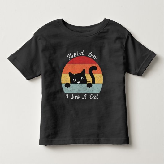 ちょっと待って、猫がいるよ。遊び好きでユーモアのある猫がこっちを見てる! トドラーTシャツ (正面)