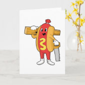 のこぎりと木材を持つ大工のホットドッグ カード (黄色い花)