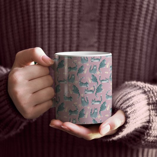 ひどい灰色のタビー猫が物を倒す コーヒーマグカップ