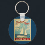 アウターバンクスSailboat Vintage Travel North Carolina キーホルダー<br><div class="desc">The Greeting From Outer Banksノースカロライナのヴィンテージ旅行デザイン航海のは、海の上を帆走する船と豪華で膨らんだ白い雲で満ちた青い空を特徴としている。</div>