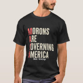 アメリカを牛耳る馬鹿者たち 風刺グラフィック Tシャツ (正面)