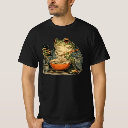 イライラカエルが日本のラーメンを食べスマホをスクロール Tシャツ (正面)