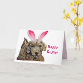 イースターにおめかししたゴールデンドゥードル ピンクのウサギ耳がキュート カード (黄色い花)