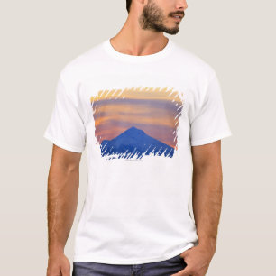 オレンジ空の雪によっておおわれる青い山 Tシャツ