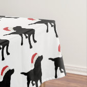 クリスマスのサンタクロースの帽子を身に着けている黒い実験室犬 テーブルクロス (インサイチュ)