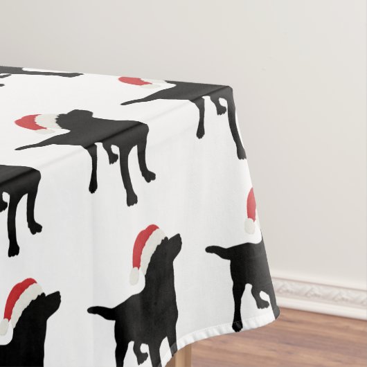 クリスマスのサンタクロースの帽子を身に着けている黒い実験室犬 テーブルクロス (インサイチュ)