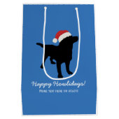 クリスマスのサンタクロースの帽子を身に着けている黒い実験室犬 ミディアムペーパーバッグ (裏面)