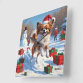 クリスマスの帽子をかぶったパピヨンの犬が雪の中を走る スクエア壁時計 (傾斜)