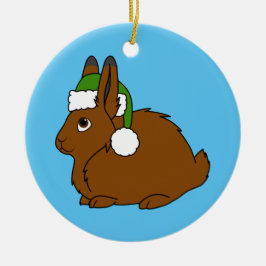 クリスマスの緑のサンタの帽子が付いているブラウンの北極ノウサギ セラミックオーナメント