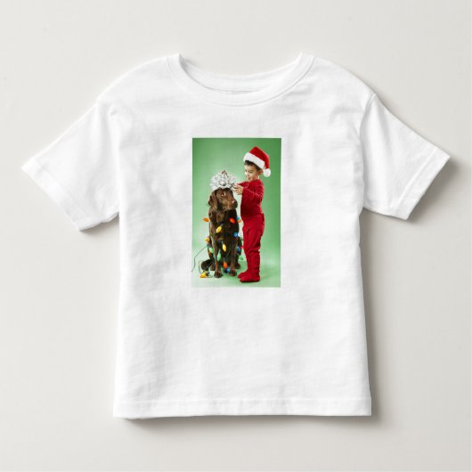 クリスマスを飾る若い男のまわりにの子が犬を照らす トドラーTシャツ (正面)