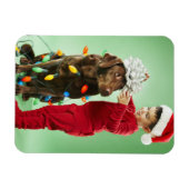 クリスマスを飾る若い男のまわりにの子が犬を照らす マグネット (横)