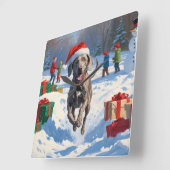 クリスマスハットをかぶった雪の中を走るワイマラナー スクエア壁時計 (傾斜)