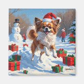 クリスマス帽子をかぶったパピヨンの犬が雪の中を走る マグネット (正面)