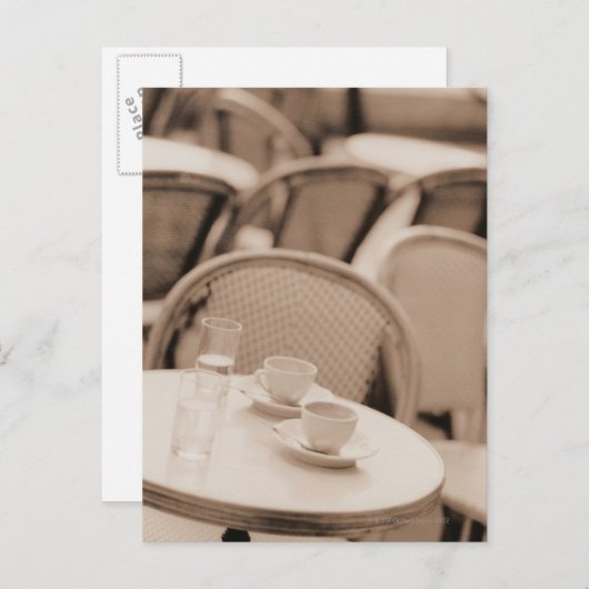 コーヒーカップとグラスを歩道のカフェテーブルに ポストカード (正面/裏面)
