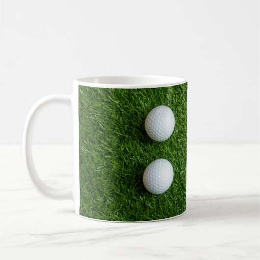ゴルフボールが緑の芝生の上に コーヒーマグカップ (左)