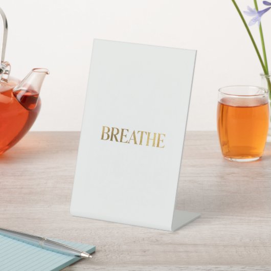 ゴールドの文字で"breathe"と書かれたミニマリストのタイポグラフィ 台座サイン (インサイチュ)