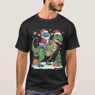 サンタのトカゲがプレゼントを持ったティラノサウルスに乗っている Tシャツ