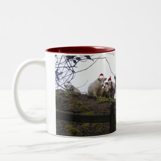 サンタの帽子のクリスマスのギフトのマグを身に着けている牛 ツートーンマグカップ (左)