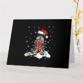 サンタハットのギフを持つかわいいシュナウカのクリスマスライト カード (黄色い花)