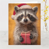 サンタ帽をかぶったかわいいアライグマがプレゼントを持っている カード (黄色い花)