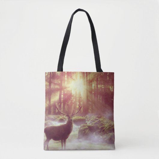 サンライズゴールデンアワーの霧の多い森の中の雄シカ トートバッグ (正面)