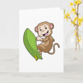 サーフボードを持つサーファーとしてのサル カード (黄色い花)