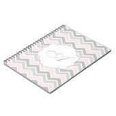 ジグザグ形のシェブロンのピンクおよび灰色のモノグラム ノートブック (左側)