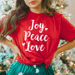 ジョイピースラブレッドブラッシュスクリプトウォメンズホリデー Tシャツ<br><div class="desc">女性の喜び平和と愛の休日のグラフィックTシャツスタイリッシュホワイトブラシ付きスクリプモダントのキュートなハートアクセント。赤いTシャツの色がカスタマイズあり。</div>