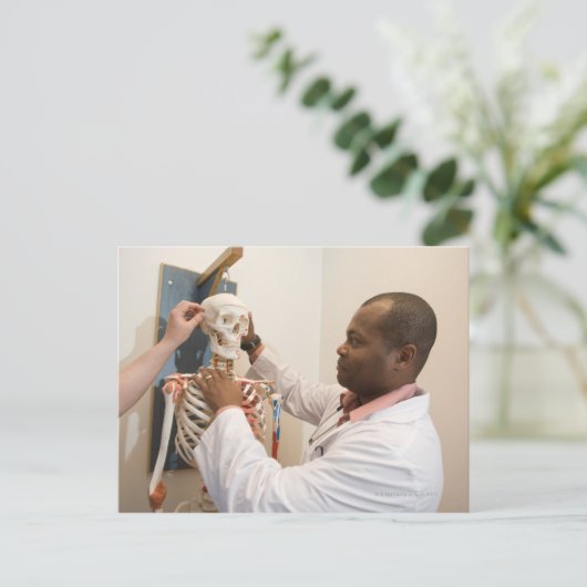 スケルトンの解剖学を研究している学生の医師 ポストカード (スタンド正面)