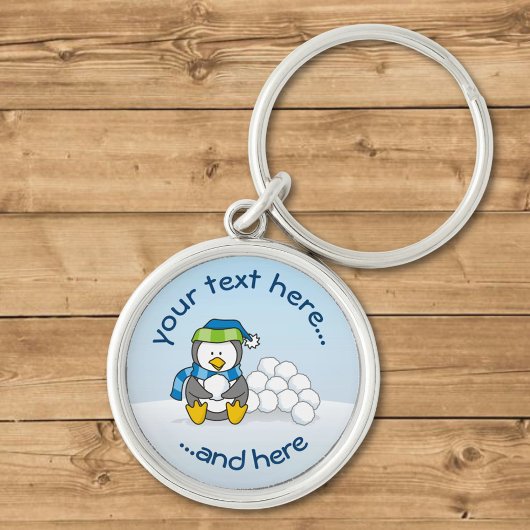 スノーボールを持って座っている小さなペンギン キーホルダー