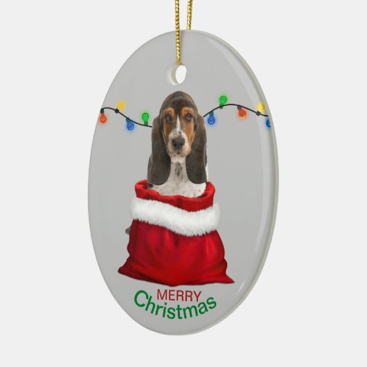 バスケット・ハウンドの子犬がクリスマスプレゼント袋に入ったクリスマス セラミックオーナメント (左)
