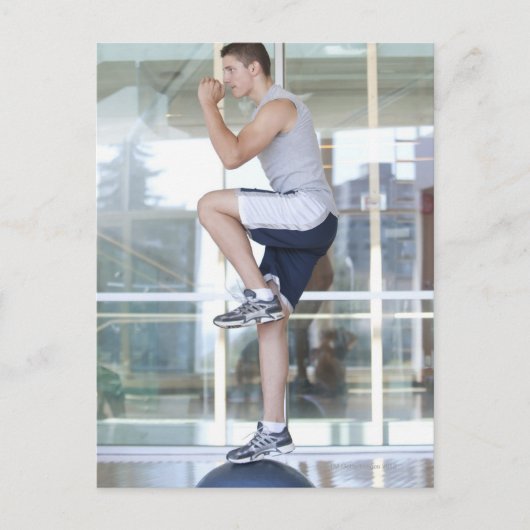 バランスを取ってステップアップエクササイズをする若者 ポストカード (正面)