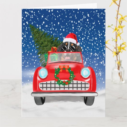 バーニーズ・マウンテン・ドッグが雪の中で車を運転するクリスマス カード (黄色い花)