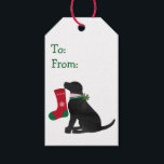 パーソナライズされたChristmas Black名門私立校風の Lab Dog ギフトタグ<br><div class="desc">パーソナライズされたフェスティバルキュート名門私立校風のなブラックラボ口にクリスマスストッキングを持つ。おもしろいの休日プレゼント!犬™名門私立校風のデザイン© EMRデザイン。</div>