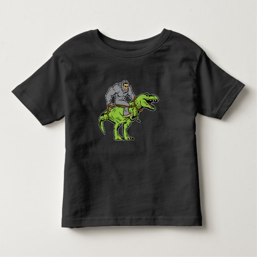 ビッグフットのサスカッチの乗馬の恐竜Tのレックス トドラーTシャツ (正面)