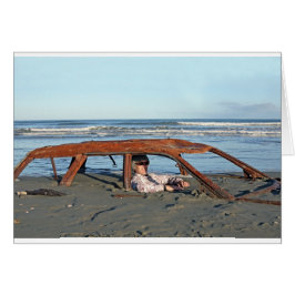 ビーチで錆びた車に座っている男