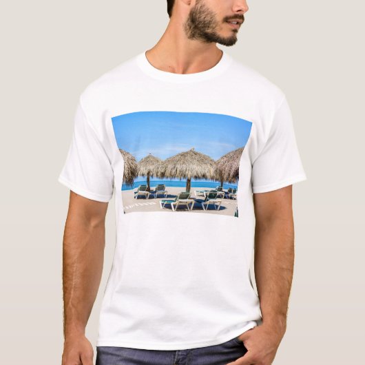 ビーチのラウンジチェアそして屋根ふき材料の傘 Tシャツ (正面)