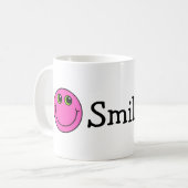 ピンクの微笑のEmojiは直面します コーヒーマグカップ (正面左)