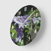 フェンス上の紫色のクレマチスの花 ラウンド壁時計 (傾斜)