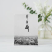 フックから吊り下げられたカメラを持つ写真家 ポストカード (スタンド正面)