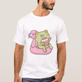 フラミンゴのプールフロートでくつろぐかわいいカエル Tシャツ (正面)