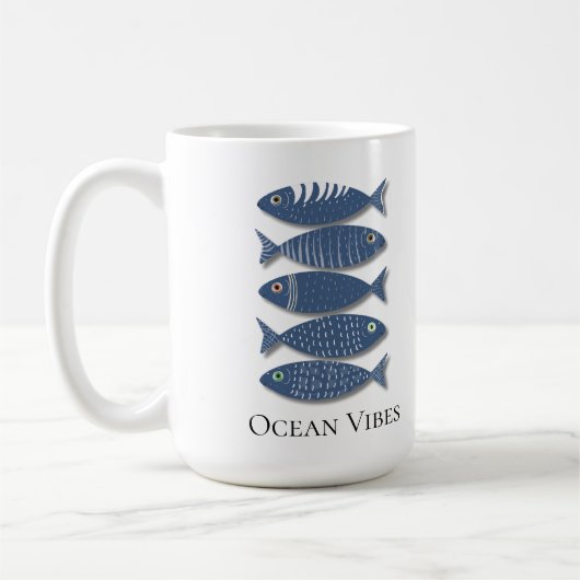 ベージュ地にコスタルブルーの魚の模様 コーヒーマグカップ (左)