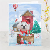 マルチーズの犬が雪のそばのクリスマスツリーと犬小屋に座っている カード (黄色い花)