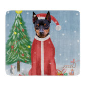 ミニチュア・ピンシュの雪にクリスマスのプレゼントを贈る犬 カッティングボード (正面)