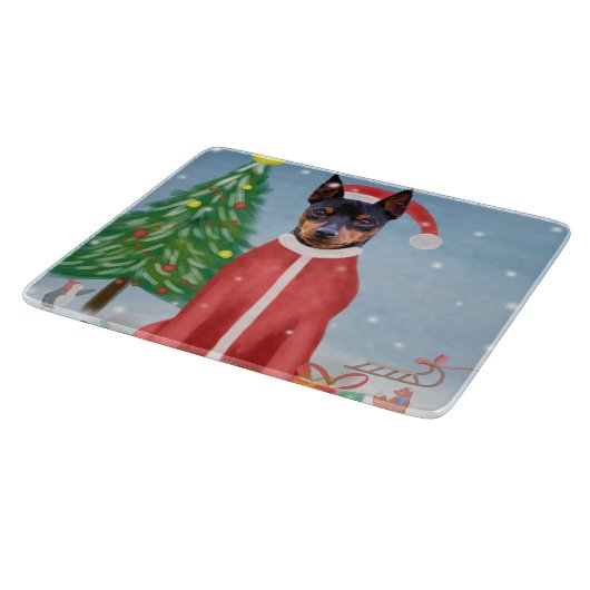 ミニチュア・ピンシュの雪にクリスマスのプレゼントを贈る犬 カッティングボード (角)