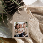 モダンBeige Merry Christmas Photo ギフトタグ<br><div class="desc">私たちのスタイリッシュベージュメリークリスマスギフトのラベルでモダンあなたの贈り物にtouchを追加。ベージュの背景に白いセリフレタリングで「メリークリスマス」を飾ったエレガントこのラベルは休日にぴったりだ。おカスタマイズ名前と個人touchの家族の写真背景には白いドットが付いた微妙な降雪パターンが映し出され、フェスティバルの外観が完成。今シーズンの中で暖かさと魅力を加えるのに最適！</div>