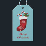 レッドクリスマスストッキングオンブルー – Merry Christmas ギフトタグ<br><div class="desc">デステイのオリジナルイラストレーションのフェスティバルレッドのクリスマスストッキングで、そこから2つのキャンディ来ーの甘い菓子を持つ。背景色は青。現在はパーソナル化された文字エリア読も存在する： "Merry Christmas".</div>